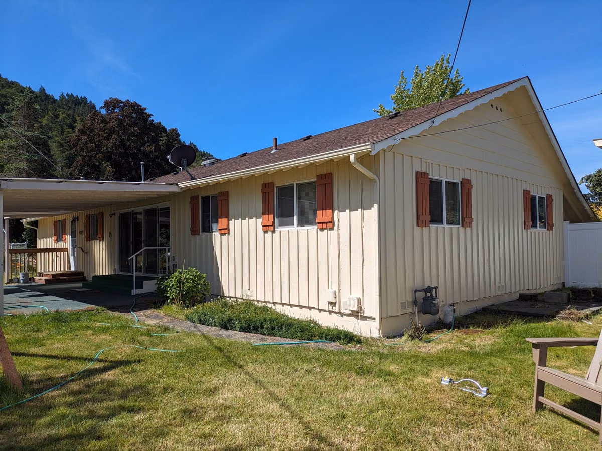 Back of the same ranch home after painting, with terracotta shutters