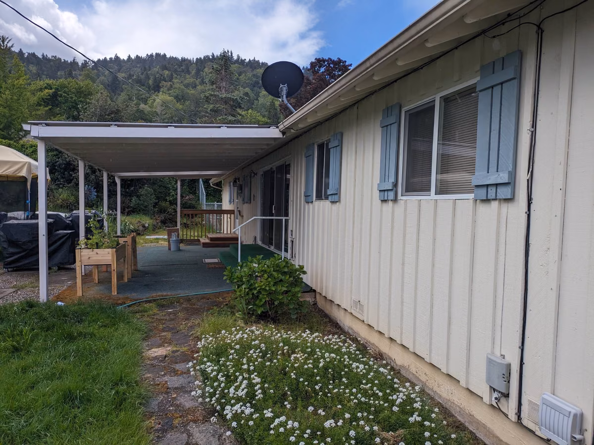 Back of a ranch home before painting, with blue-gray shutters